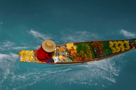 A vendor on a boat selling fresh fruit